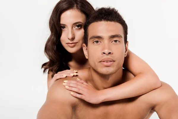 Atractiva mujer abrazando mixta raza hombre y mirando la cámara aislada en blanco - foto de stock