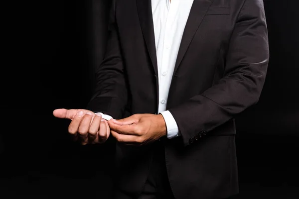 Обрезанный вид смешанной расы мужчина трогает белую рубашку, изолированную на черном — стоковое фото