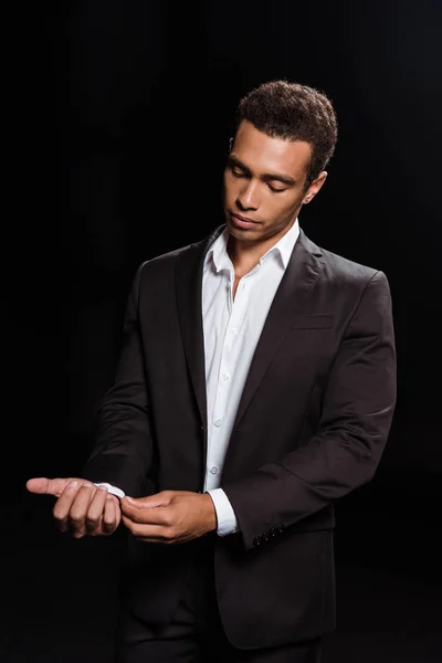 Mixed Race Mann stehend und Anzug anfassen isoliert auf schwarz — Stockfoto