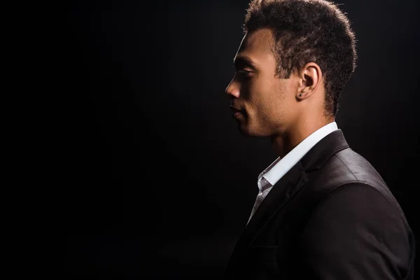 Side view of handsome bi-racial man in formal wear isolated on black — Stock Photo