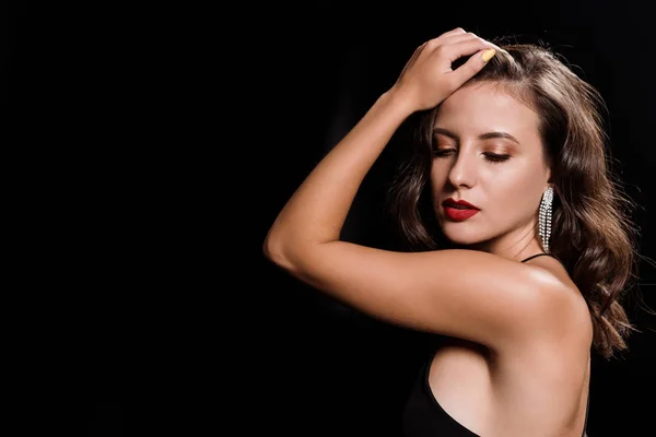 Elegante mujer joven tocando el pelo aislado en negro - foto de stock