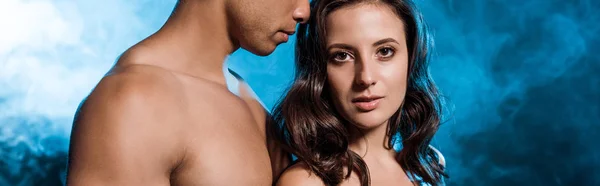 Panoramic shot of mixed race man near attractive young woman on blue with smoke — Stock Photo