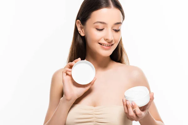 Belle jeune femme heureuse avec une peau parfaite regardant la crème cosmétique isolée sur blanc — Photo de stock