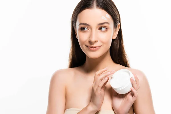 Smiling beautiful young woman with perfect skin and cosmetic cream on face looking away isolated on white — Stock Photo