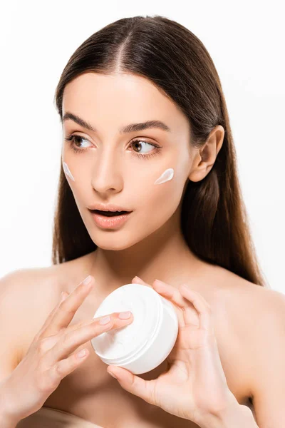 Bella giovane donna sorpresa con pelle perfetta applicare crema cosmetica isolata su bianco — Foto stock