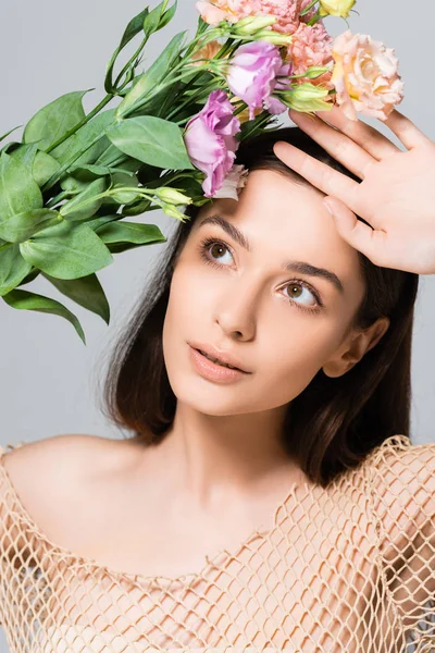 Hermosa joven en malla beige posando con ramo de flores de eustoma aisladas en gris — Stock Photo