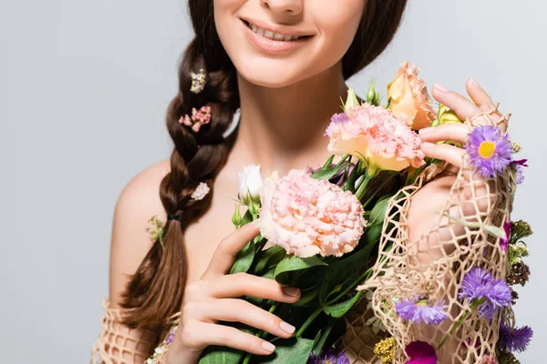 Teilansicht der schönen Frau mit Zopf in Maschen mit Frühlingswildblumen isoliert auf grau — Stockfoto