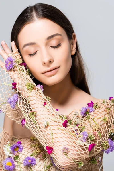 Beautiful woman with closed eyes in mesh beige clothing with purple flowers posing isolated on grey — Stock Photo