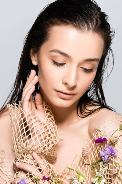 Hermosa mujer en malla de ropa beige con flores púrpuras aisladas en gris - foto de stock