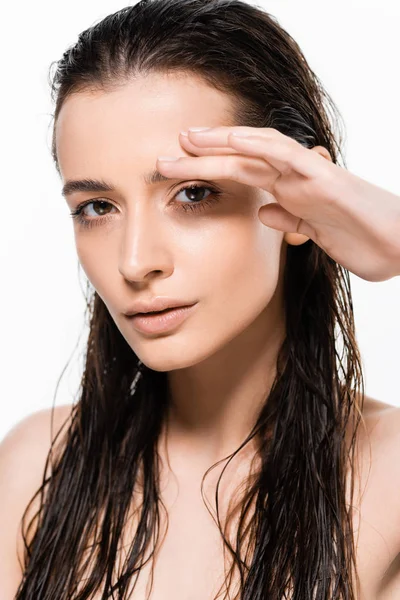 Красивая мокрая обнаженная молодая женщина с рукой возле лица, смотрящая на камеру, изолированную на белом — стоковое фото