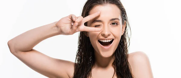 Beautiful wet young woman winking and showing peace sign isolated on white, panoramic shot — Stock Photo