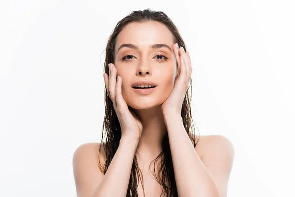 Beautiful wet nude young woman touching face and looking at camera isolated on white — Stock Photo