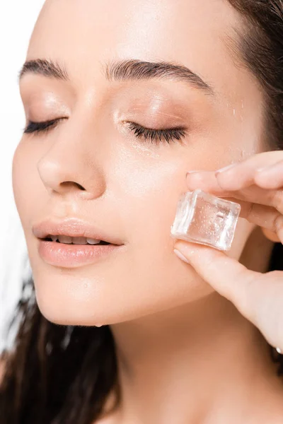 Morena húmeda mujer joven con los ojos cerrados y cubo de hielo aislado en blanco - foto de stock