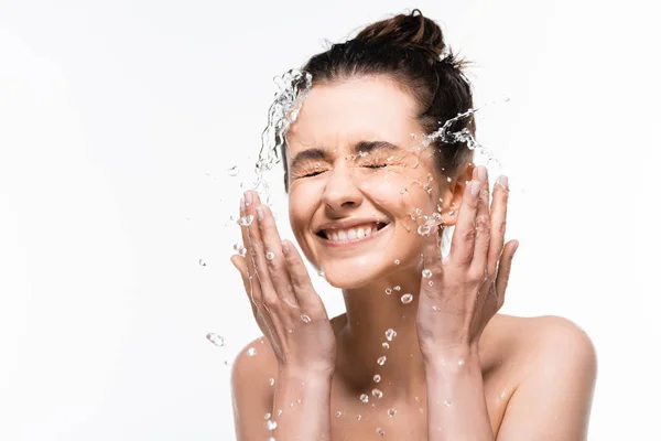 Щаслива гола молода жінка з природною красою, що миється з чистими бризками води ізольована на білому — стокове фото