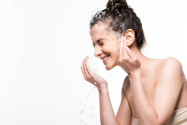 Glücklich junge brünette Frau mit natürlicher Schönheit Abwasch mit sauberem Wasser spritzt isoliert auf weiß — Stockfoto