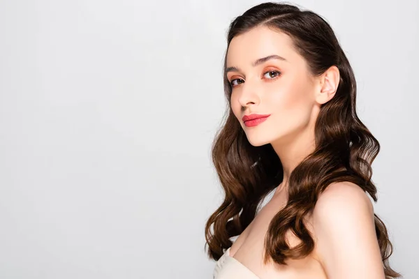 Side view of beautiful brunette woman with curls and makeup isolated on grey — Stock Photo