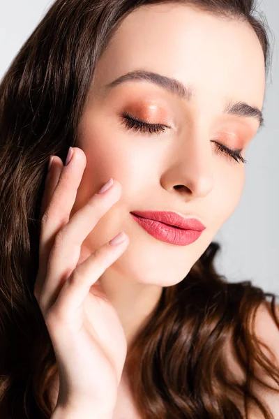 Schöne brünette Frau mit geschlossenen Augen und glänzendem Make-up isoliert auf grau — Stockfoto