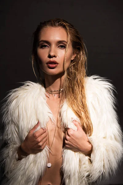 Sexy nu jovem mulher com molhado loira cabelo com as mãos no branco falso casaco de pele isolado no preto — Fotografia de Stock