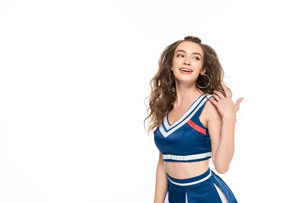 Sexy felice cheerleader ragazza in uniforme blu guardando lontano e toccando i capelli isolati su bianco — Foto stock