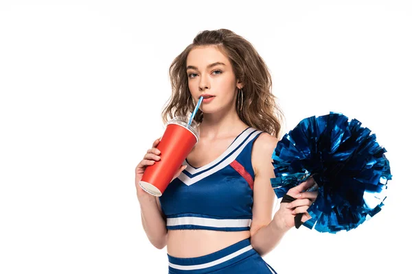 Cheerleader girl in blue uniform holding pompom and drinking soda isolated on white — Stock Photo