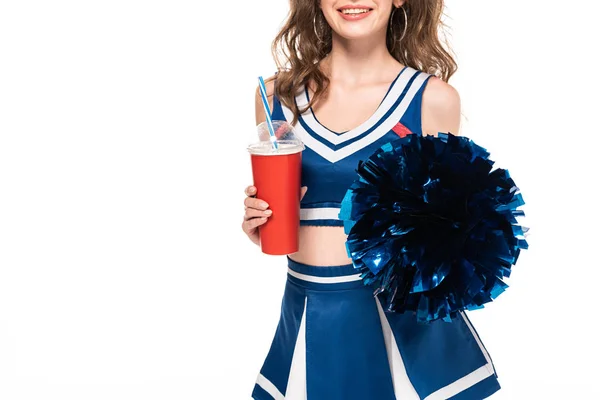 Обрізаний вид щасливої дівчини-вболівальниці в блакитній формі, що тримає помпон і соду в паперовій чашці ізольовані на білому — стокове фото