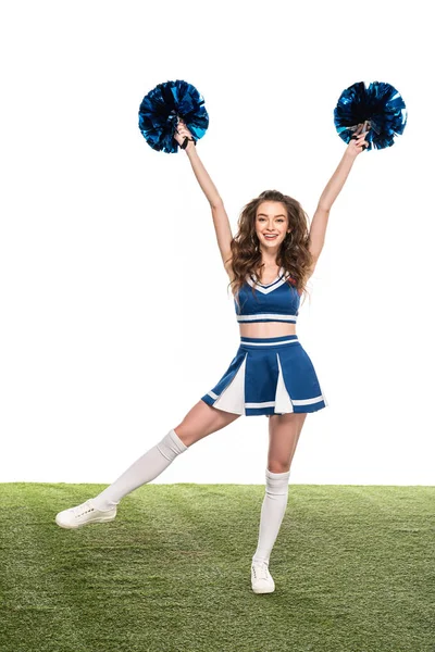 Menina cheerleader feliz em azul uniforme dançando com pompons no campo verde isolado no branco — Fotografia de Stock
