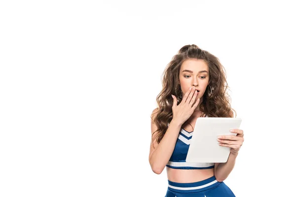 Schockiertes Cheerleader-Mädchen in blauer Uniform mit digitalem Tablet auf weißem Hintergrund — Stockfoto