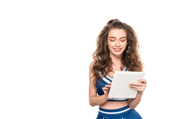 Счастливая девушка чирлидерша в синей форме, держащая цифровой планшет изолирован на белом — стоковое фото