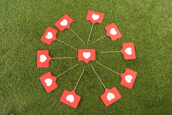 Flat lay with social media hearts signs on green field — Stock Photo