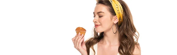 Jeune femme au foyer heureuse en robe et tablier regardant muffin isolé sur blanc, vue panoramique — Photo de stock