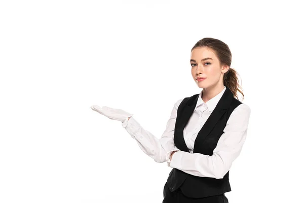 Jeune serveuse en tenue formelle et gants blancs pointant avec la main isolée sur blanc — Photo de stock