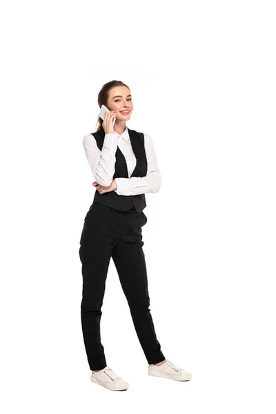 Vista completa de la joven camarera feliz hablando en el teléfono inteligente aislado en blanco - foto de stock