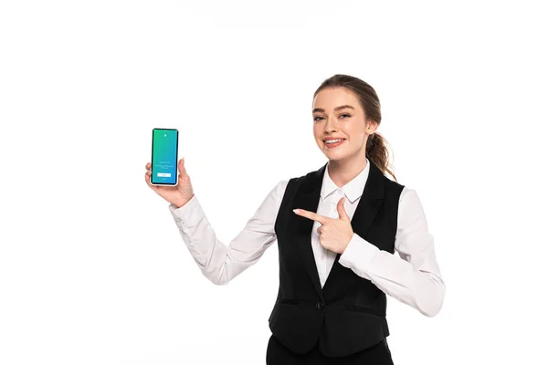 KYIV, UCRANIA - 7 DE ABRIL DE 2019: joven camarera feliz señalando con el dedo a la aplicación de twitter en el teléfono inteligente aislado en blanco - foto de stock