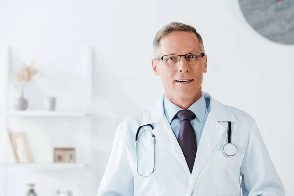 Gutaussehender Arzt mit Brille blickt im Krankenhaus in die Kamera — Stockfoto