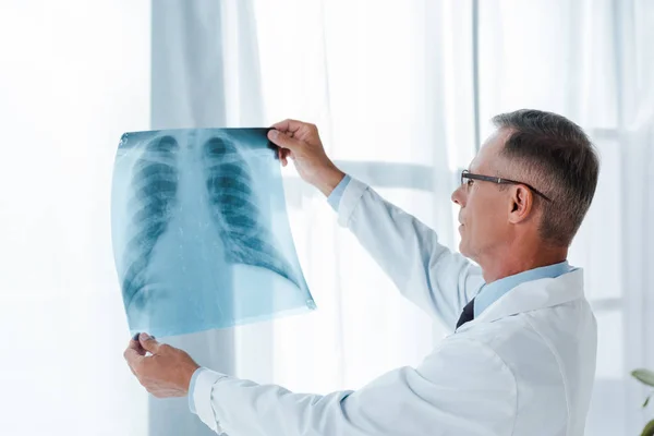 Arzt in weißem Kittel und Brille mit Röntgenbild im Krankenhaus — Stockfoto