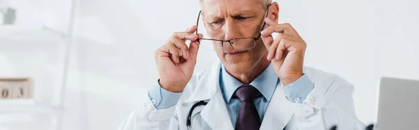 Panoramic shot of doctor in white coat holding glasses — Stock Photo