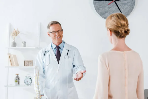 Selective focus of happy doctor gesturing while looking at woman — Stock Photo