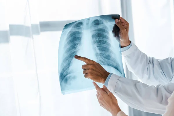 Обрізаний вид лікаря та пацієнта, який вказує пальцями на рентген у клініці — стокове фото