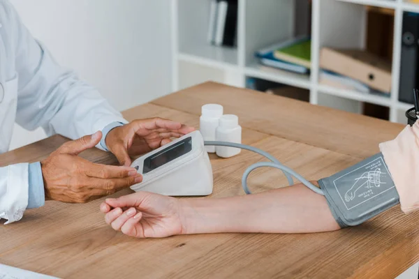 Vue recadrée du geste du médecin tout en mesurant la pression artérielle de la femme — Photo de stock