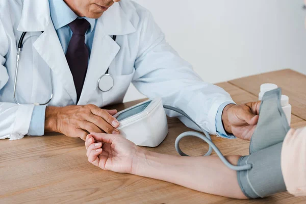 Vista ritagliata del medico che misura la pressione sanguigna del paziente in clinica — Stock Photo