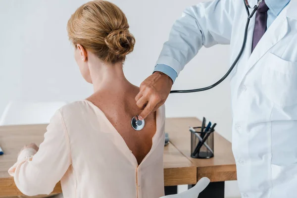 Ausgeschnittene Ansicht eines Arztes im weißen Kittel, der Frau in Klinik untersucht — Stockfoto