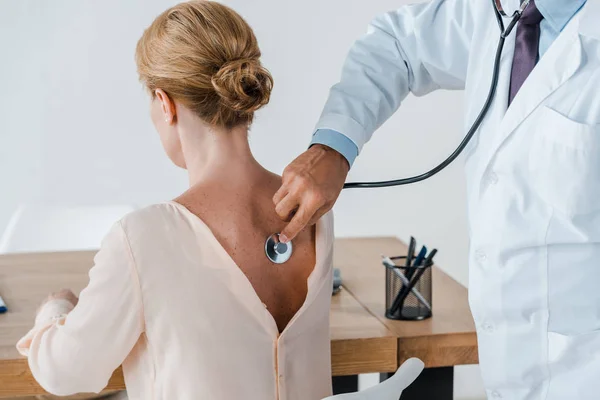 Vue recadrée du médecin en manteau blanc examinant la femme à la clinique — Photo de stock