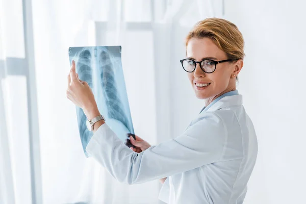 Glücklicher und attraktiver Arzt in Brille mit Röntgenaufnahme in der Klinik — Stockfoto