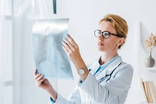 Médecin attrayant dans les lunettes à la recherche de rayons X dans la clinique — Photo de stock