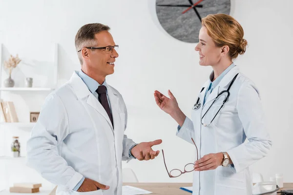 Médicos felices haciendo gestos mientras se miran en la clínica - foto de stock