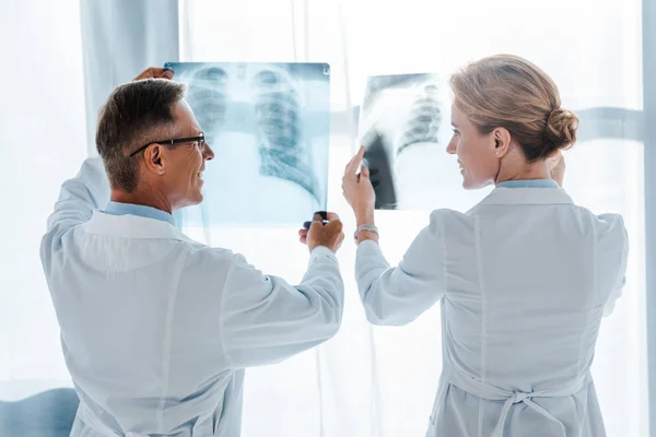 Glücklicher Arzt mit Brille und schöner Mitarbeiter mit Röntgenaufnahmen in der Klinik — Stockfoto