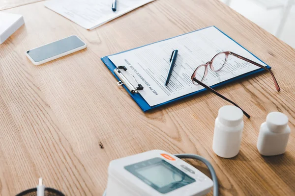 Selective focus of clipboard near pen,glasses and bottles in clinic — Stock Photo