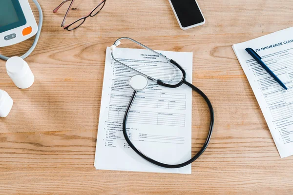 Vue du haut du stéthoscope près du smartphone avec écran vierge et documents — Photo de stock