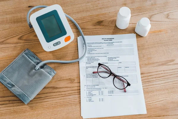 Top view of blood pressure monitor near document and glasses — Stock Photo