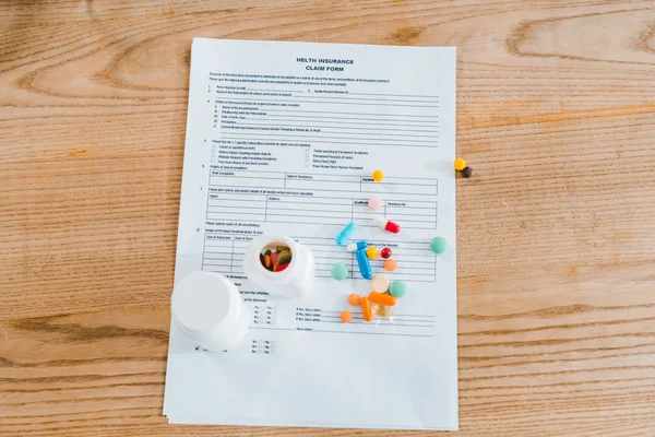 Top view of document near pills on wooden table — Stock Photo